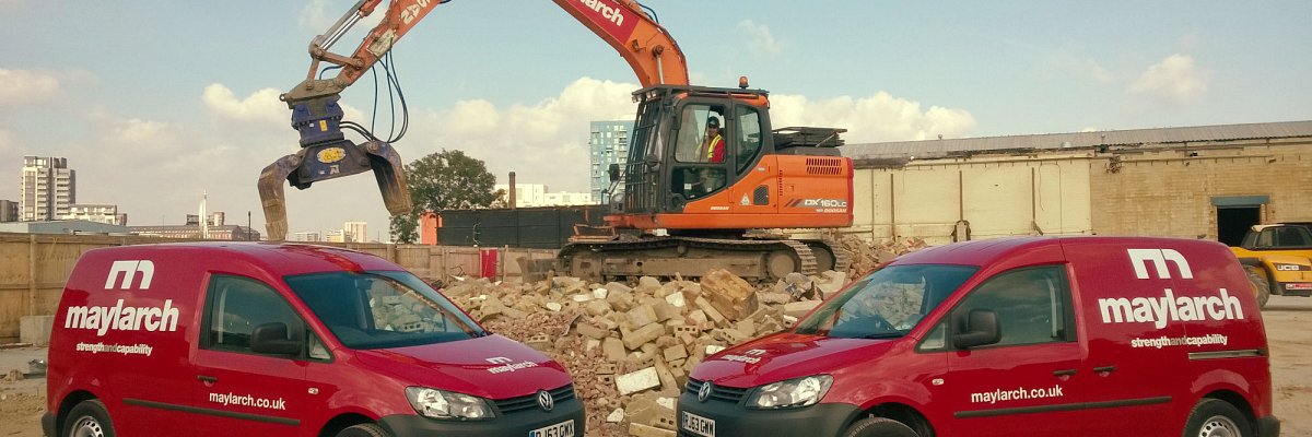 two vans in front of a digger